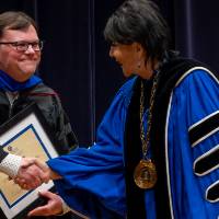 Faculty shaking President's hand